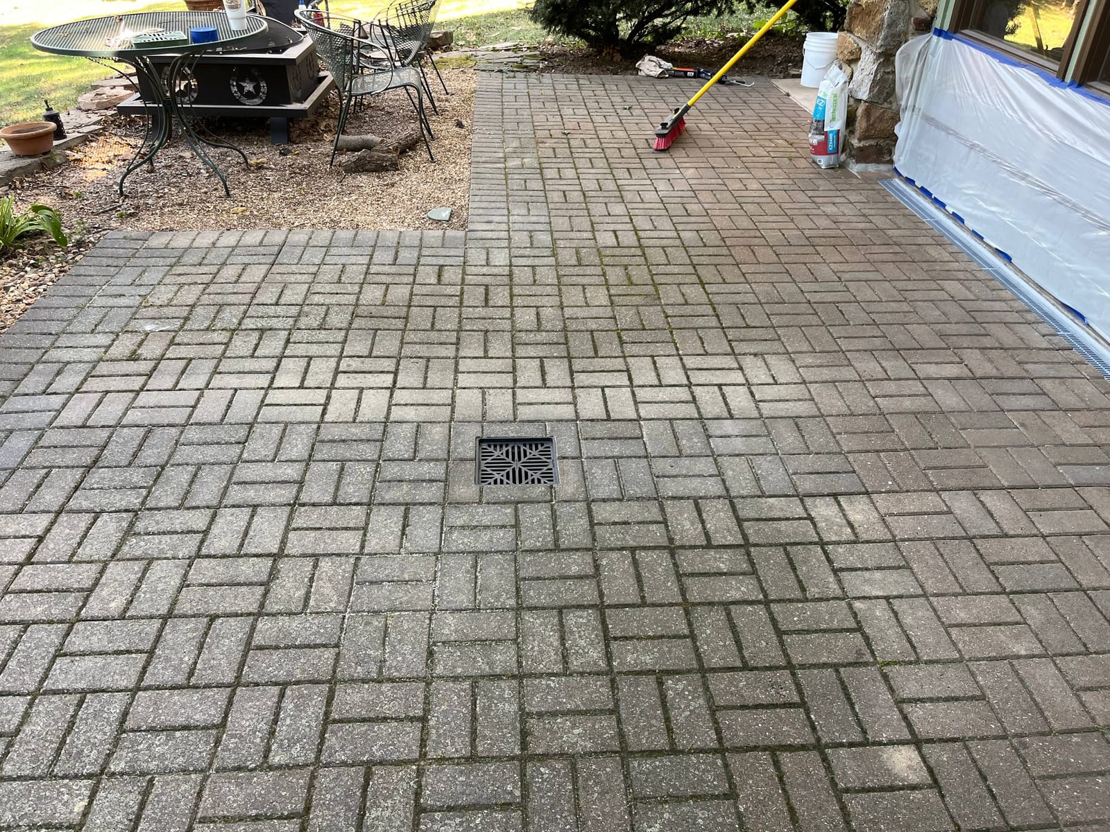 Completed brick paver patio with a catch basin grate centered in the pavers and a channel drain along the house